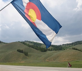 The colors in Colorado's flag represent the environmental features of the state. White symbolizes the snow on her mountains, gold acknowledges the abundant Colorado sunshine, red represents Colorado's red soil, and blue is a symbol of her clear blue 